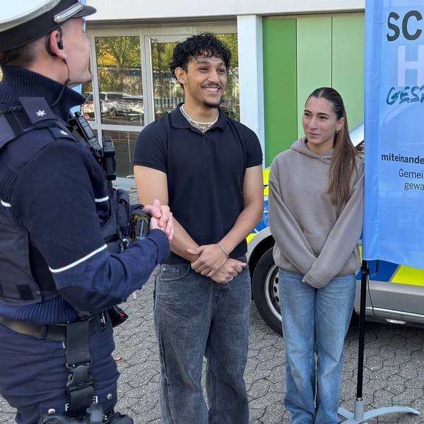 Die Polizeibeamten Jonas Tepe (l.) und Aldia Römer (2.v.r.) im Gespräch mit Gesamtschülern in Düsseldorf.