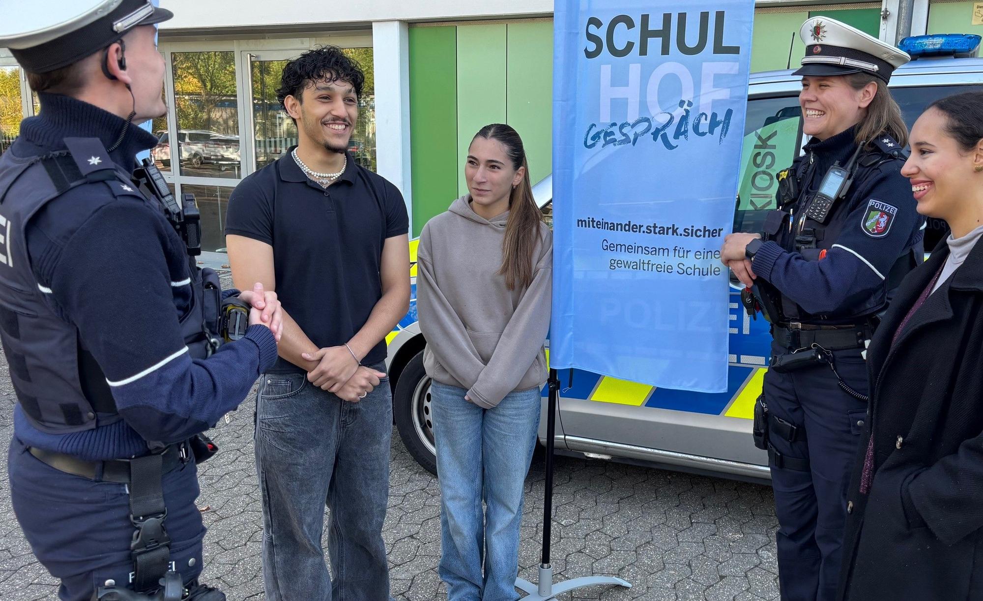 Die Polizeibeamten Jonas Tepe (l.) und Aldia Römer (2.v.r.) im Gespräch mit Gesamtschülern in Düsseldorf.