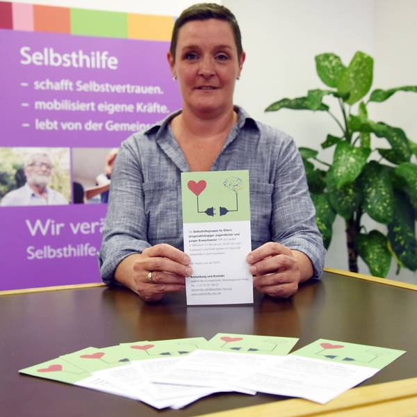 Eine Frau hält den Flyer einer neuen Selbsthilfegruppe in den Händen.