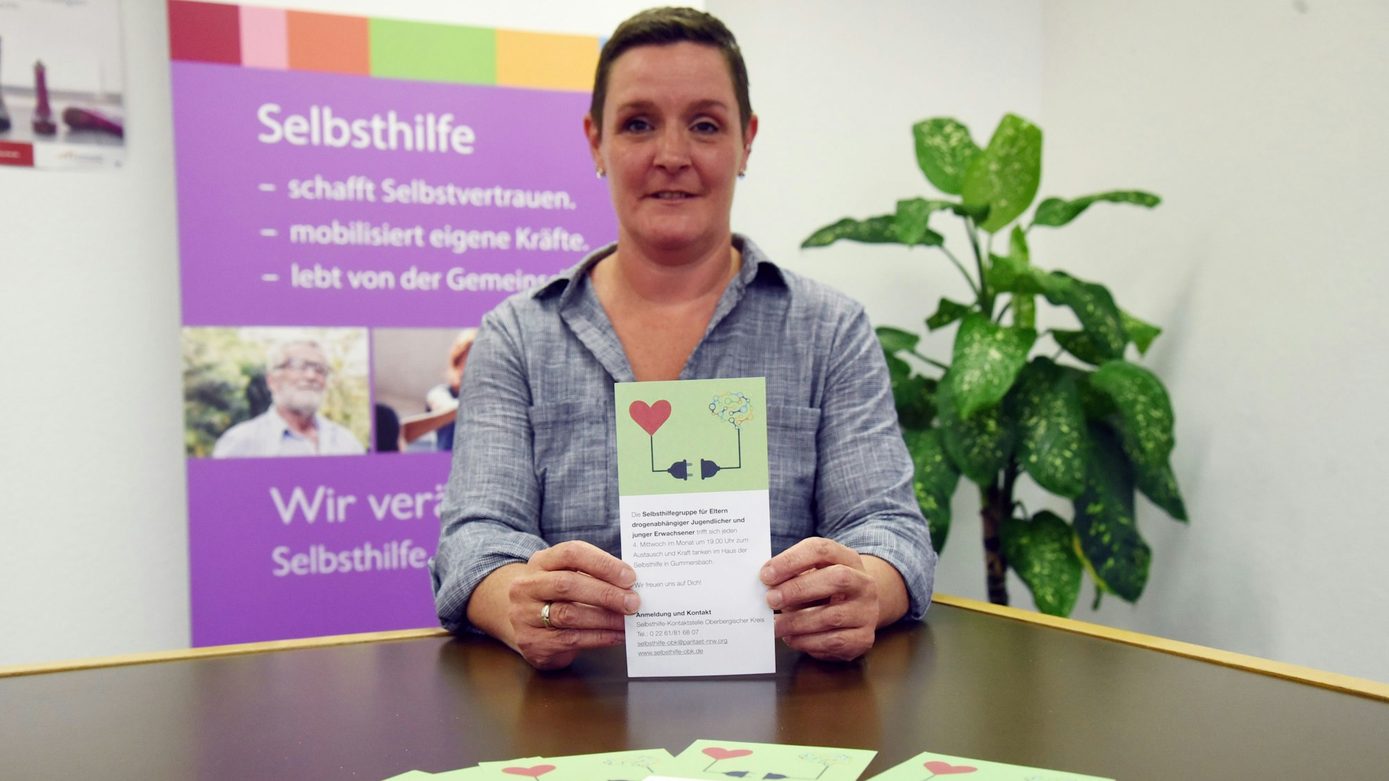 Eine Frau hält den Flyer einer neuen Selbsthilfegruppe in den Händen.