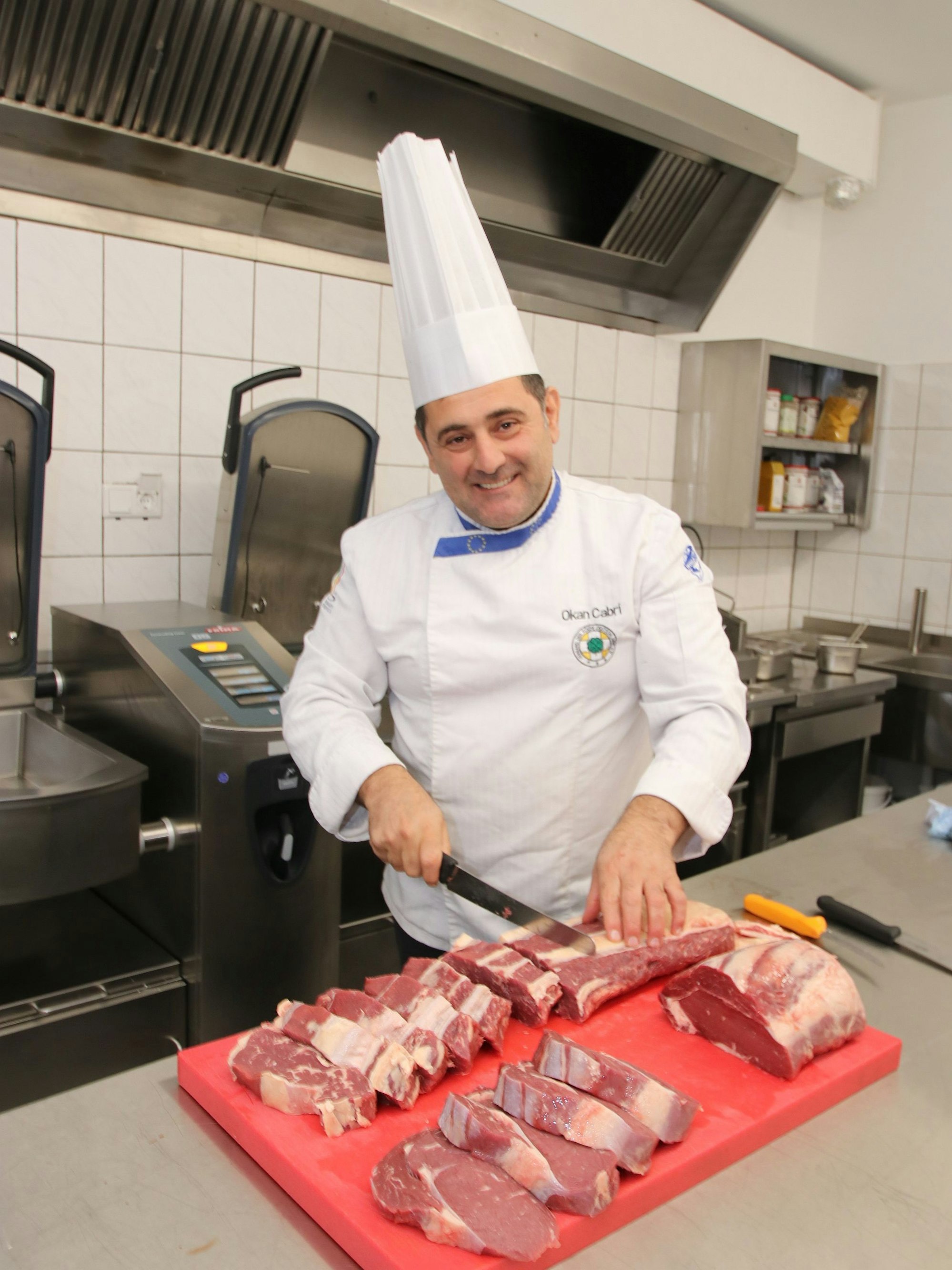Das Bild zeigt den Chef beim Schneiden von Steaks.