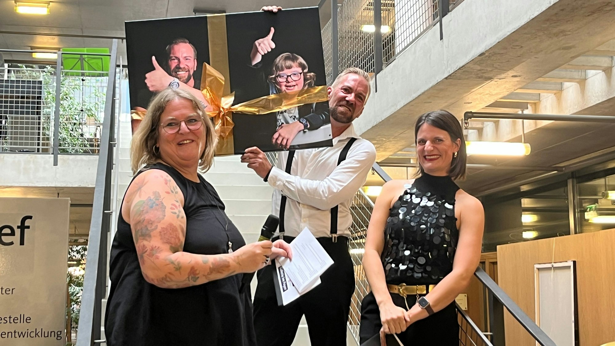 Sandra Delgado (l.) und Anna Seidel überreichten dem Fotografen Daniel Reinisch ein großformatiges Bild mit Janina.