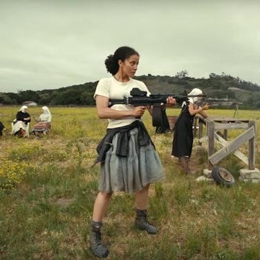 Chase Infiniti als Willa Ferguson übt sich zusammen mit einer Gruppe von Nonnen auf einer Wiese im Maschinengewehr-Schießen.