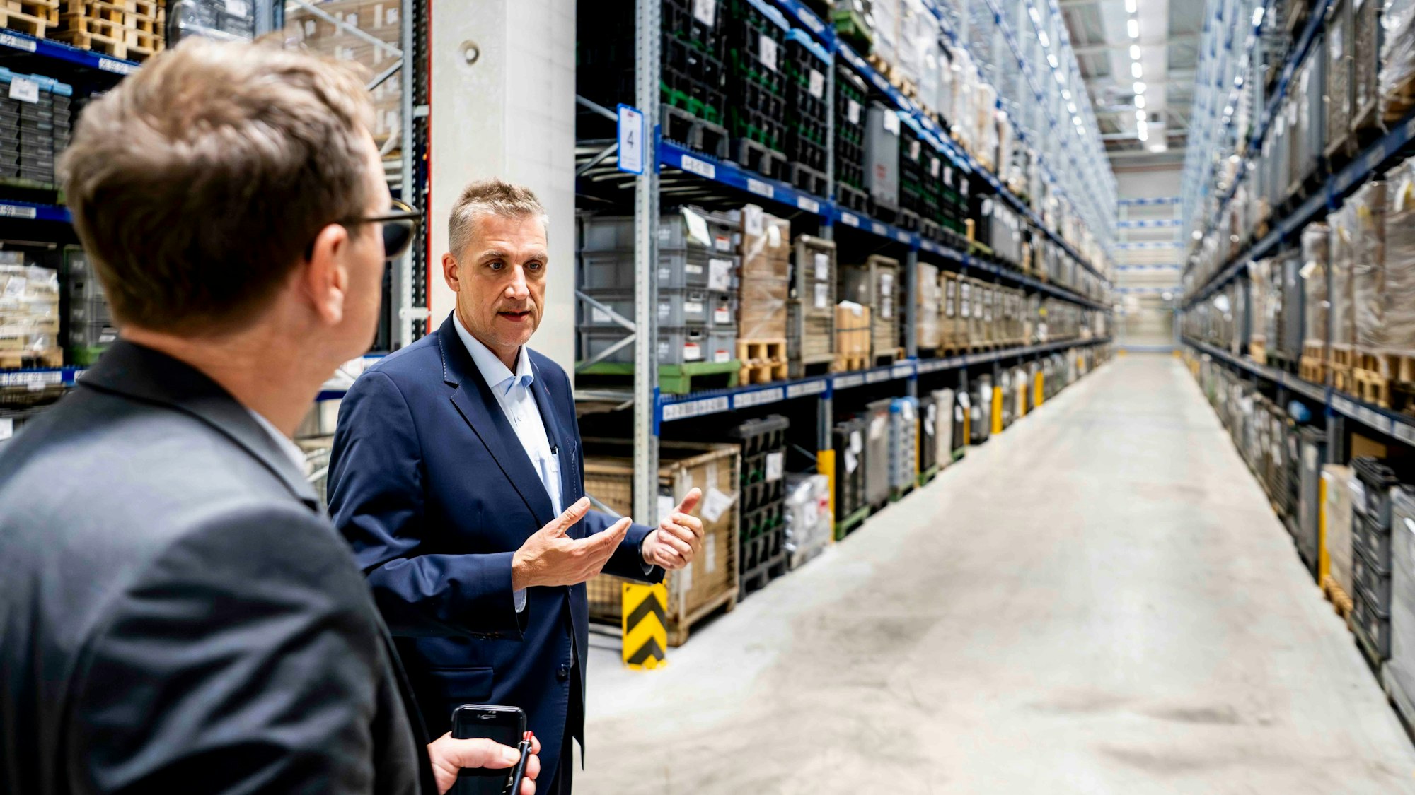 Zwei Männer im Anzug stehen im neuen Hochregallager der Firma Miele in Euskirchen.