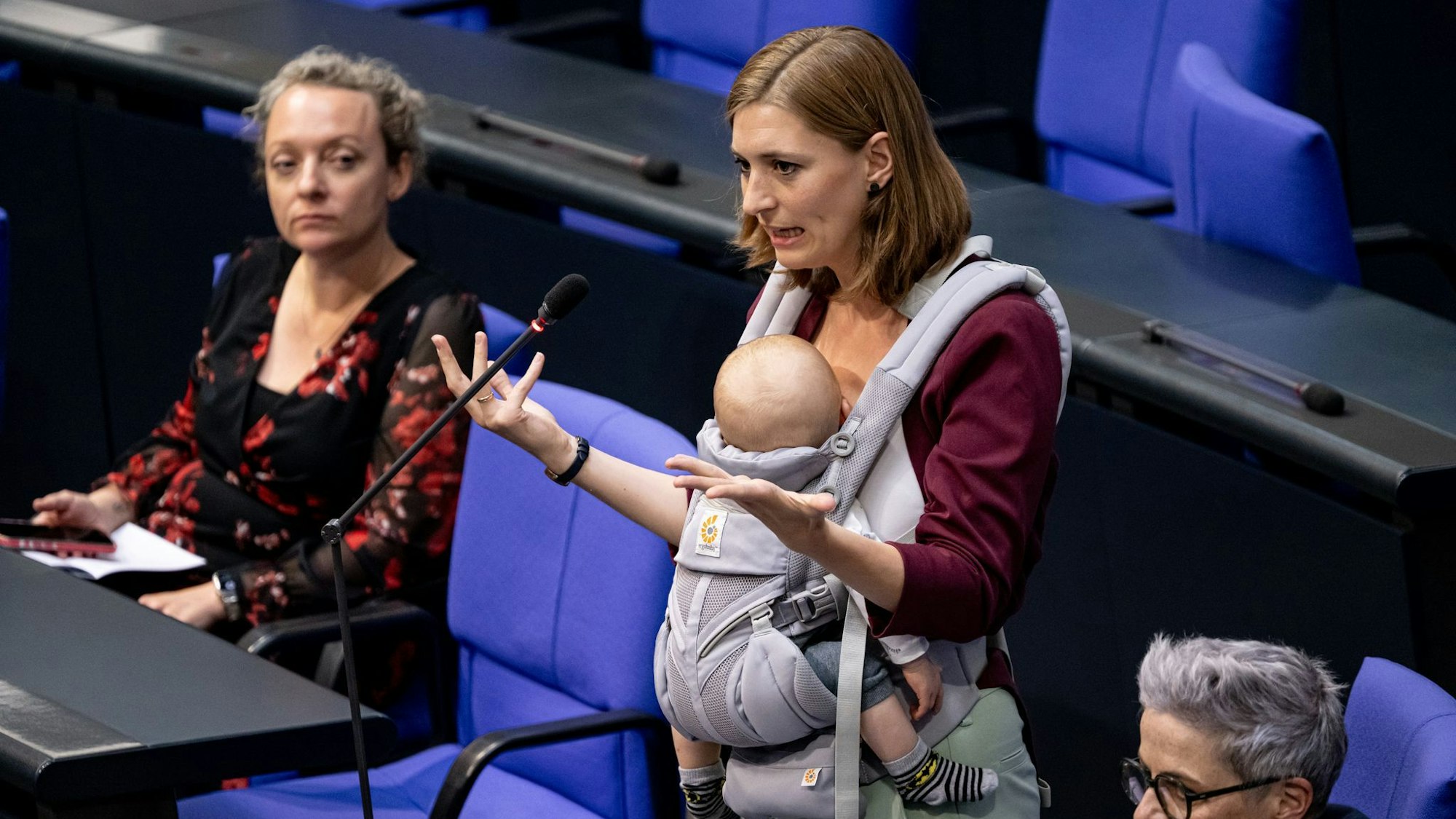 Hanna Steinmüller hält eine rede im Bundestag und trägt dabei ihr Kind vor sich in einer Trage. (Archivbild)