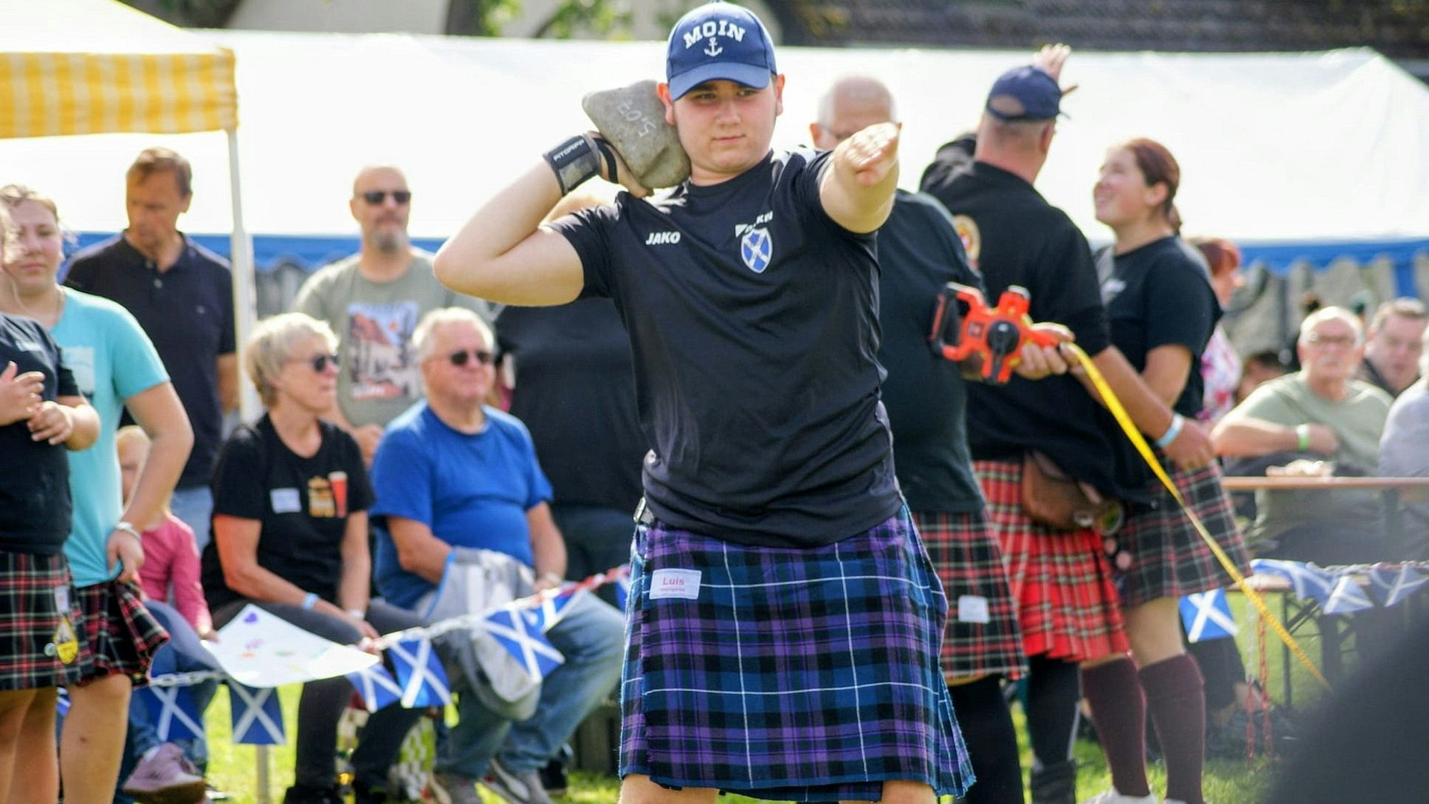 Louis Hochgürtel trägt einen blauen Kilt und eine Baseballkappe, während er zum Steinstoßen bei den Highland Games antritt.