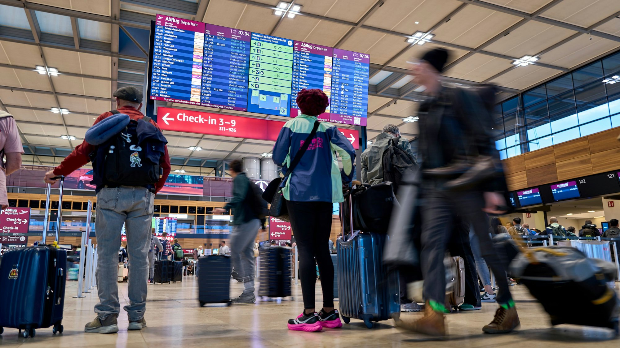 Fluggäste informieren sich nach einem Cyberangriff an den Abflugtafeln im Terminal 1 des Flughafens Berlin-Brandenburg.