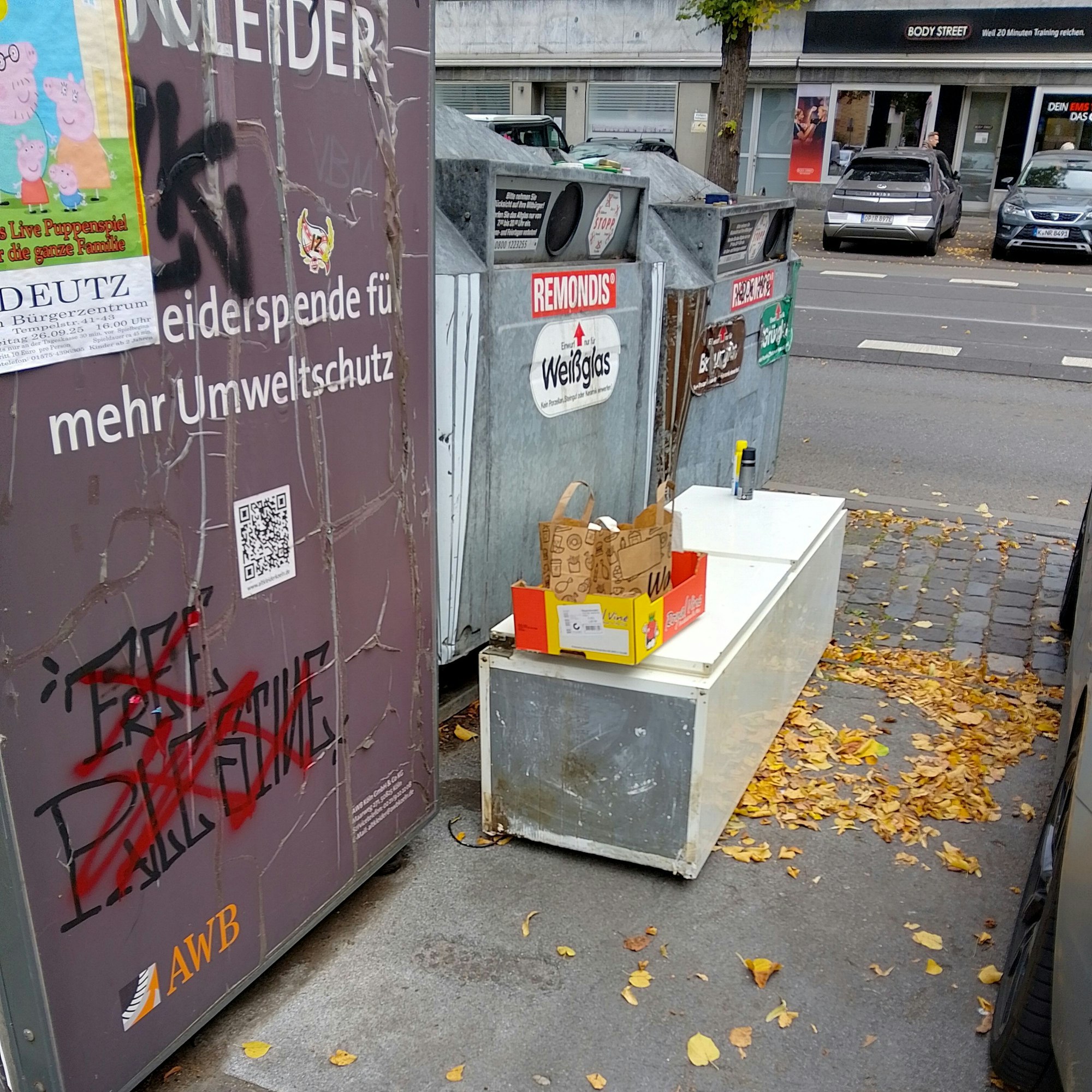 Ein alter Kühlschrank liegt vor Glascontainern auf der Straße.