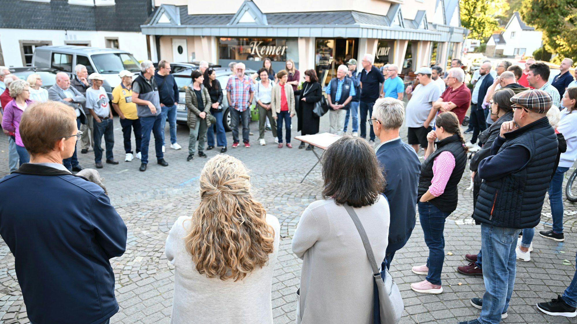 Menschen stehen auf einem Platz und diskutieren miteinander.
