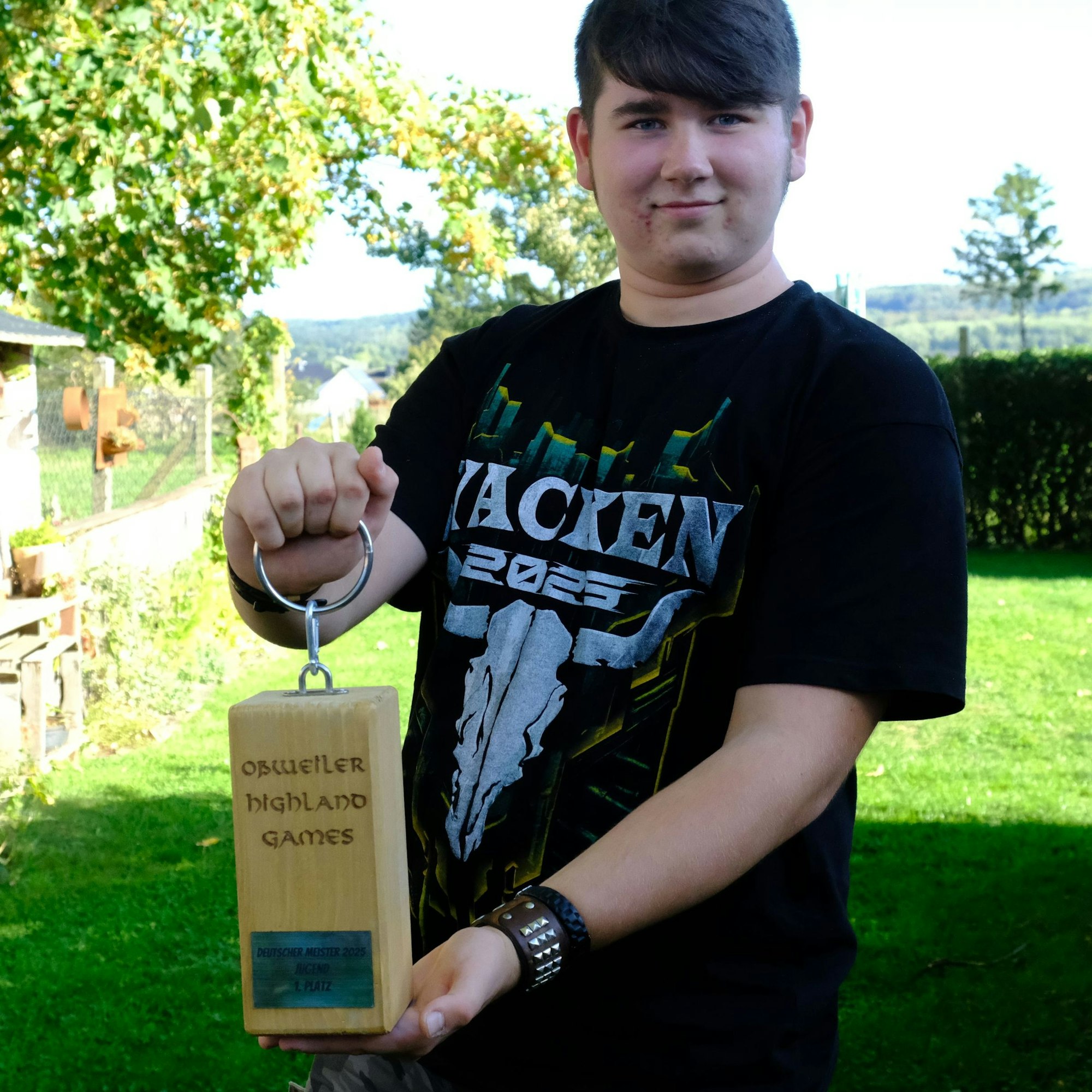 Louis Hochgürtel trägt ein schwarzes Wacken-T-Shirt und präsentiert im heimischen Garten in Hostel seine Meister-Trophäe.