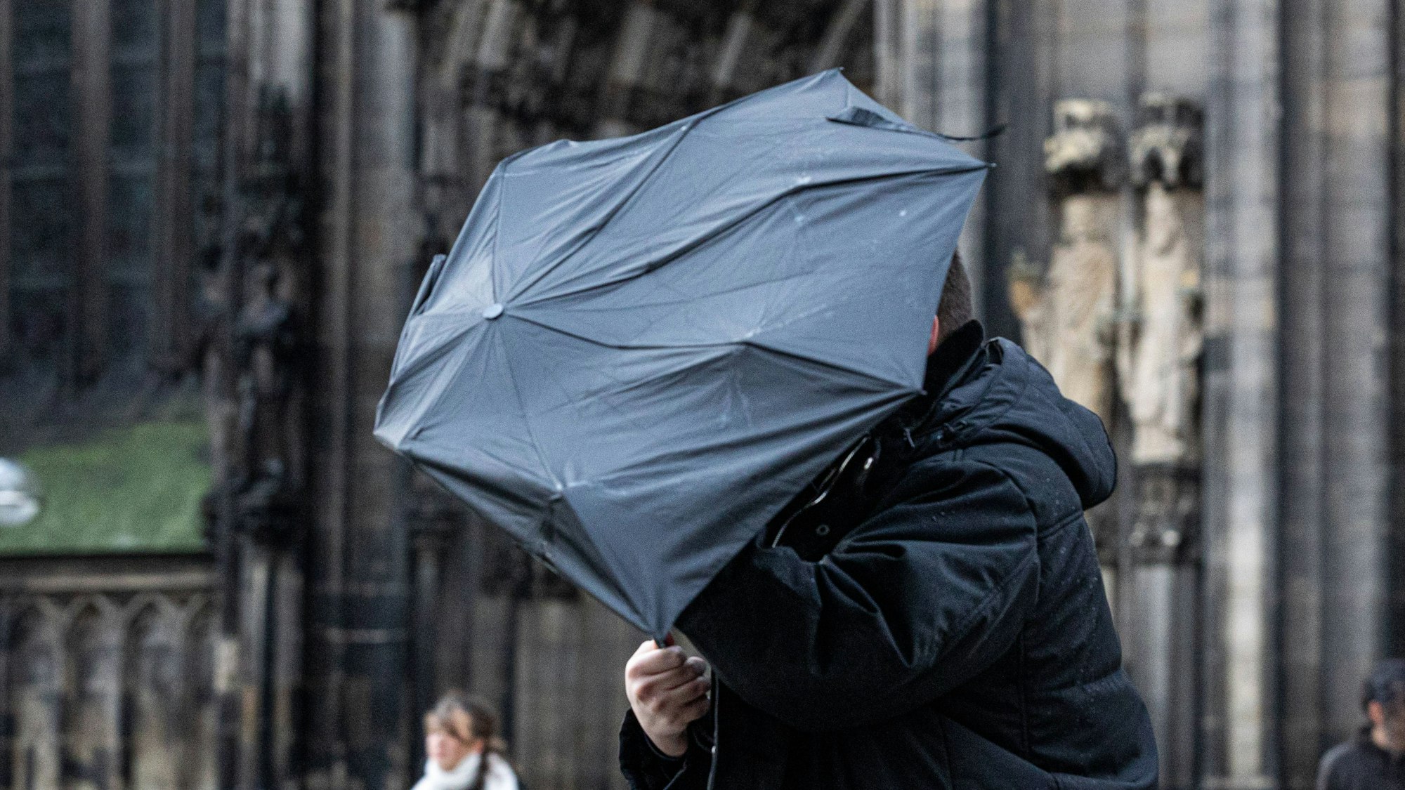 Person mit Schirm vor dem Kölner Dom.
