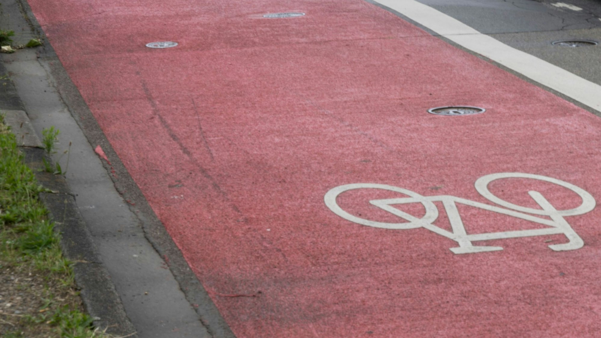 Ein rosafarbener Radweg auf einer Straße.