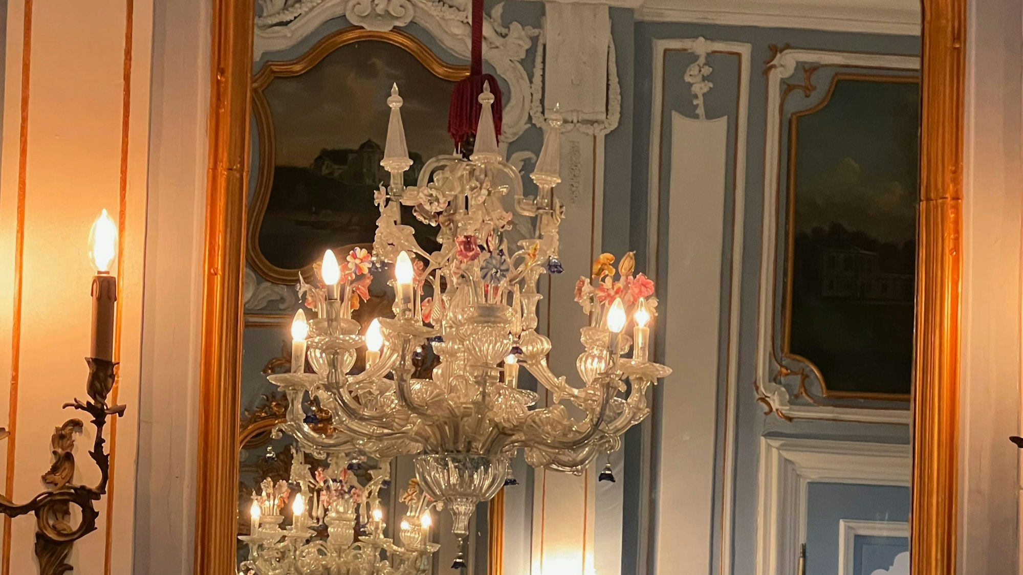 Ein Kronleuchter spiegelt sich in einem Spiegel.