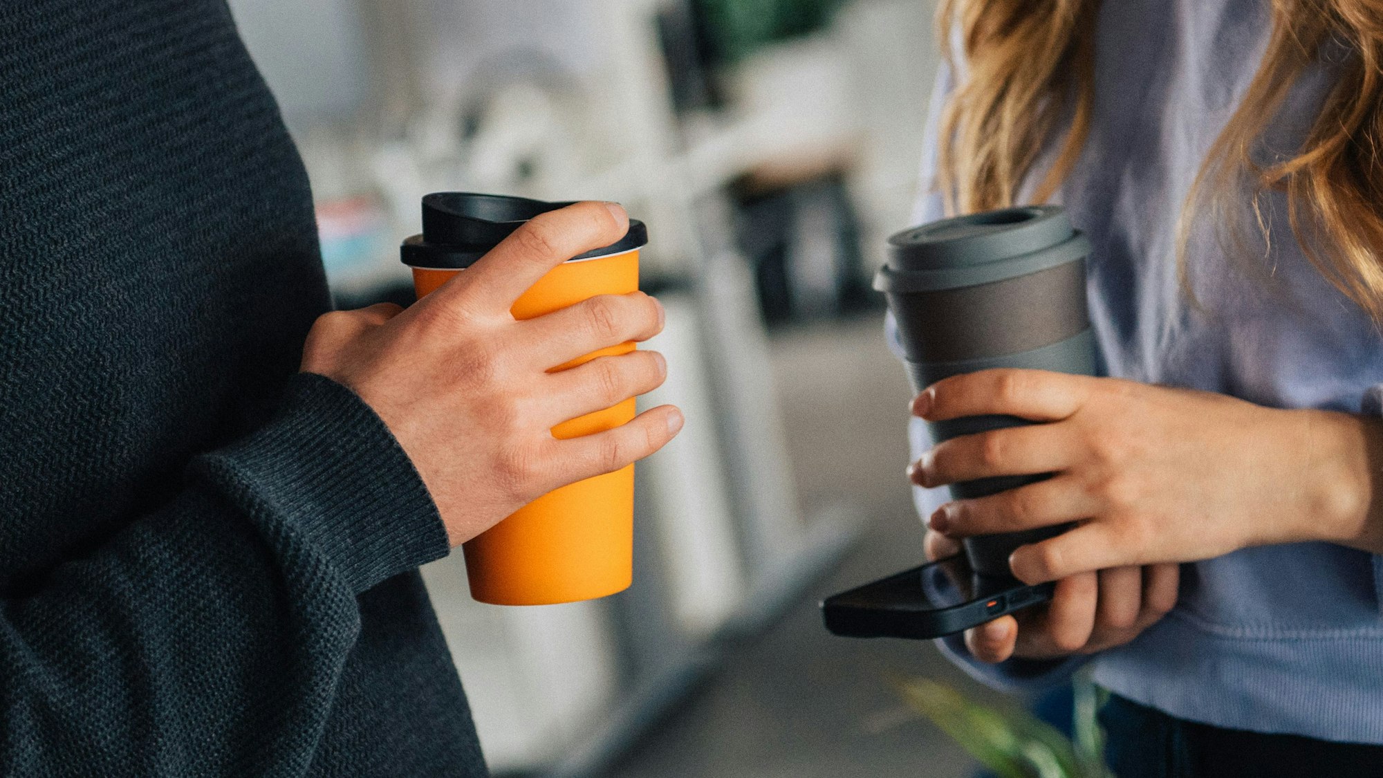 Zwei Menschen sind sich zugewandt und halten dabei einen Coffee-to-Go.