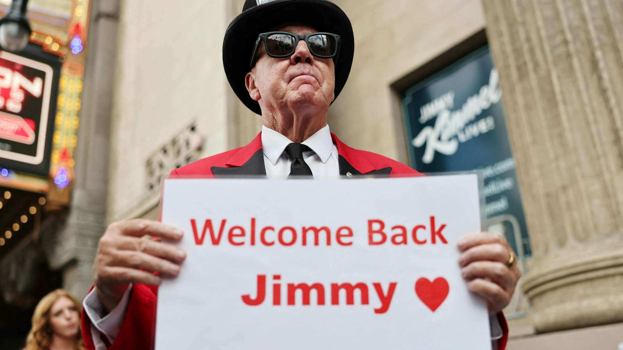 Greg Donovan zeigt ein Schild mit der Aufschrift „Welcome Back Jimmy” vor dem El Capitan Entertainment Centre in Hollywood, wo die Show „Jimmy Kimmel Live!” am ersten Abend ihrer Rückkehr ins Programm von ABC am 23. September 2025 in Los Angeles aufgezeichnet wurde.