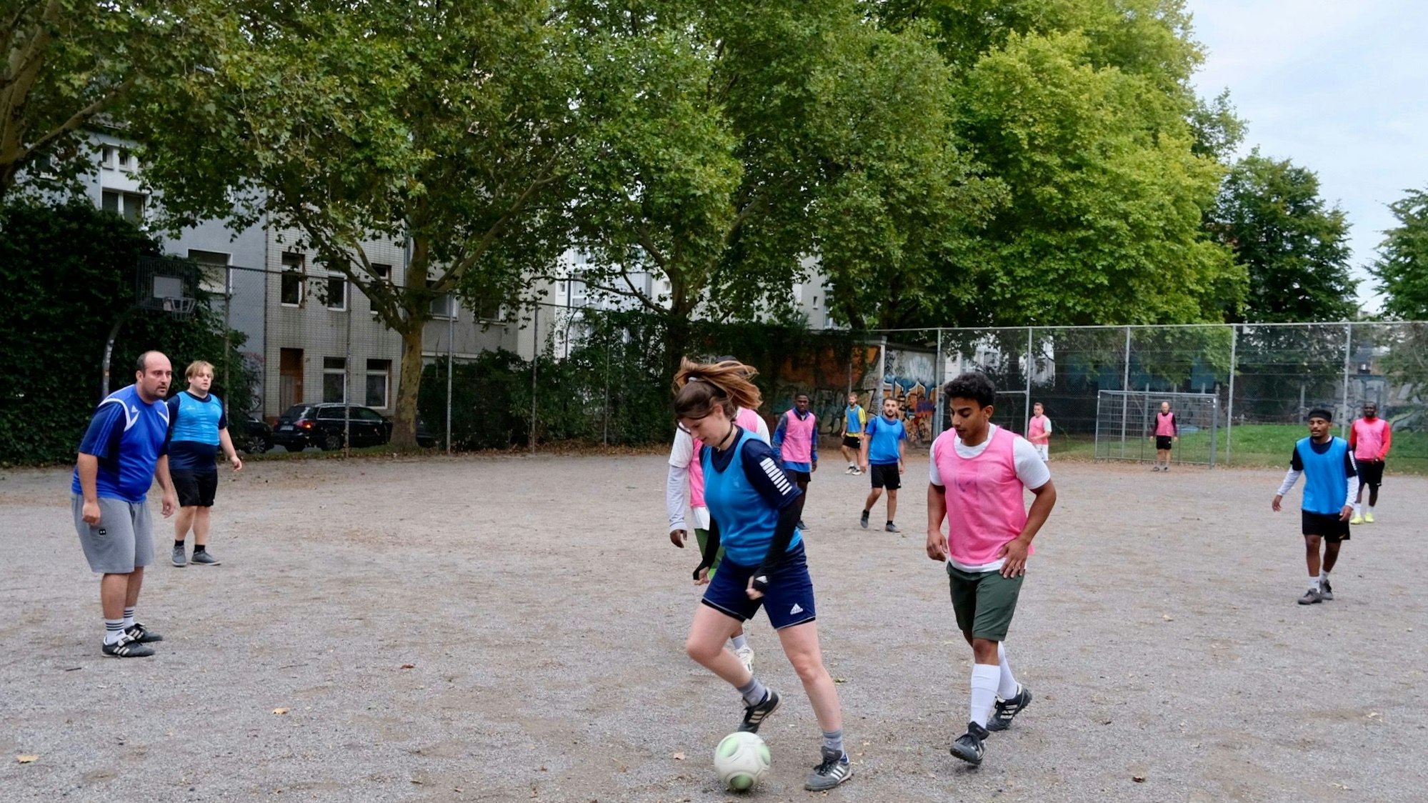 Männer und Frauen unterschiedlicher kultureller Herkunft spielen gemeinsam Fußball.