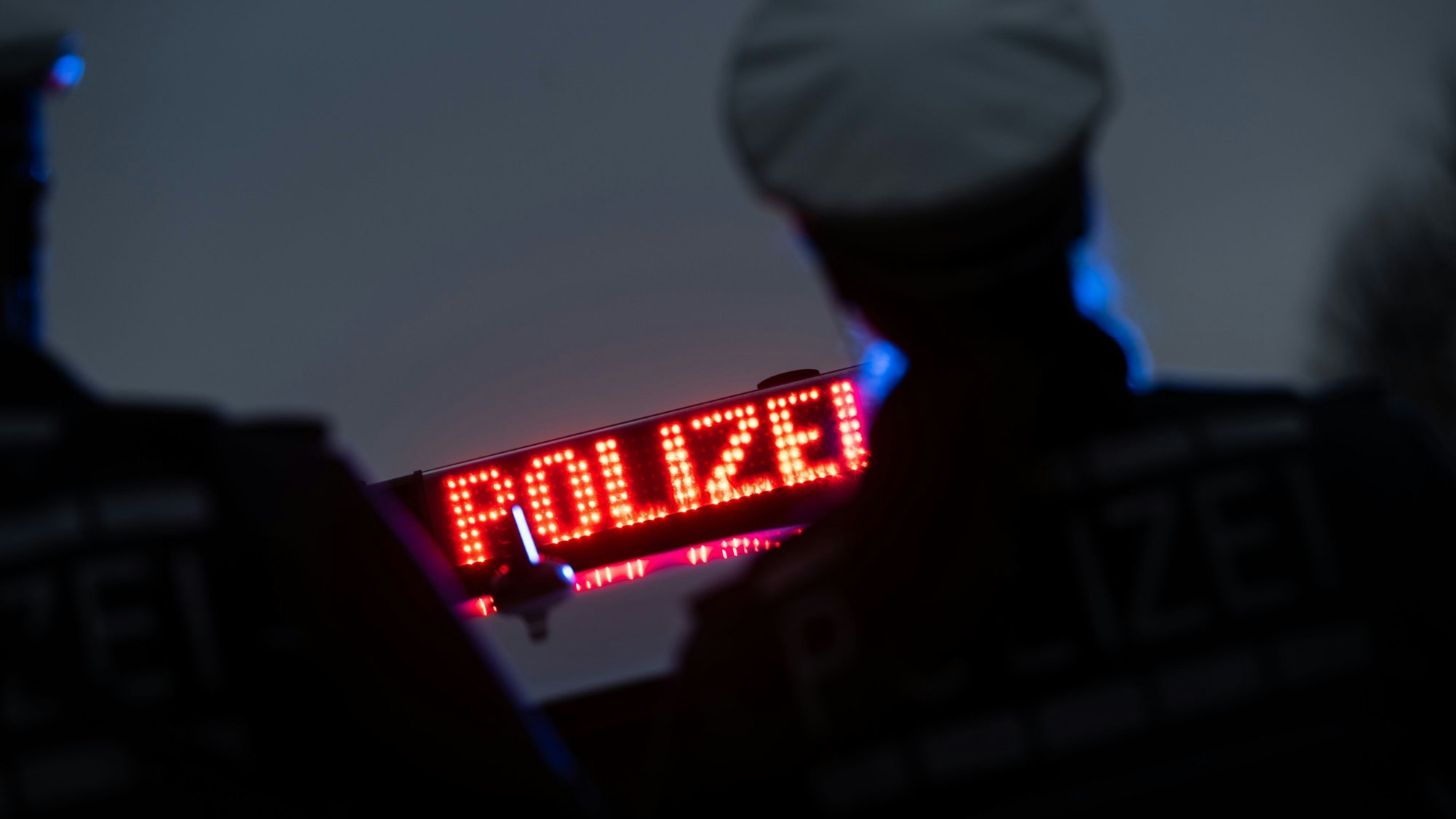Zwei Polizisten stehen vor einem Polizeifahrzeug. (Symbolbild)