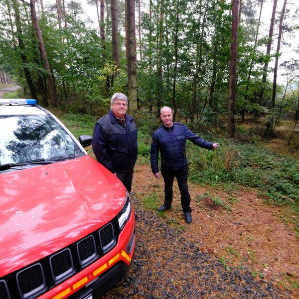 Ordnungsamtsleiter Harald Heinen (l.) und Bürgermeister Hermann-Josef Esser stehen in einem Waldgebiet in der Nähe von Kall neben einem Feuerwehr-Jeep.