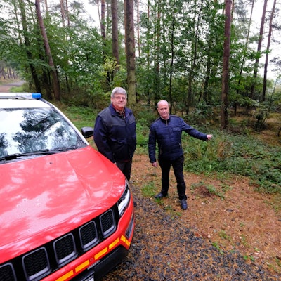 Ordnungsamtsleiter Harald Heinen (l.) und Bürgermeister Hermann-Josef Esser stehen in einem Waldgebiet in der Nähe von Kall neben einem Feuerwehr-Jeep.