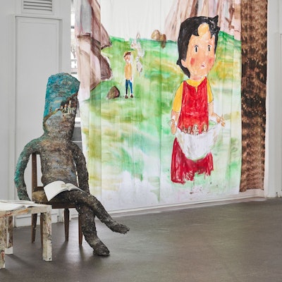 Eine Papierfigur sitzt vor einer gemalten Heidi.