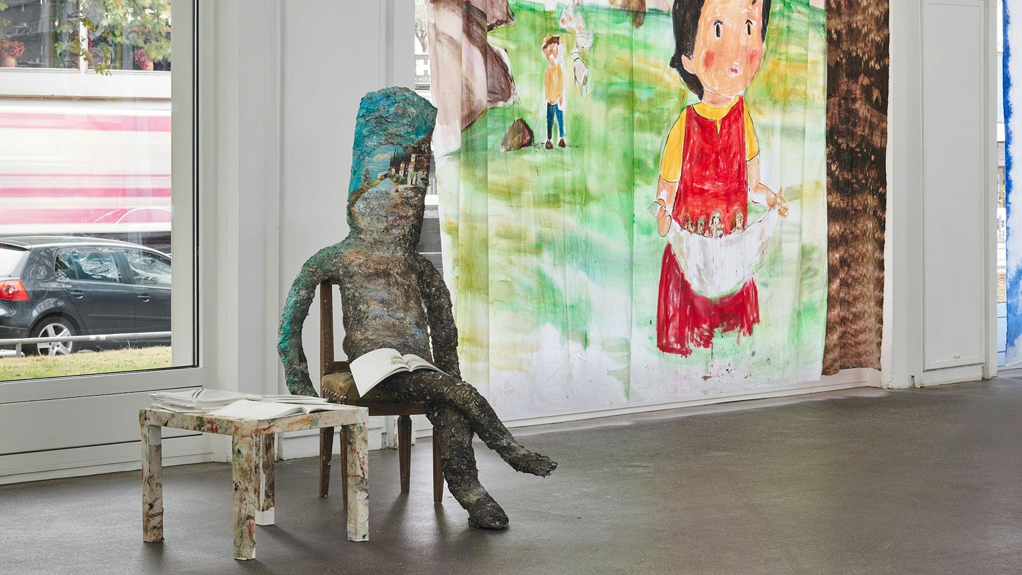 Eine Papierfigur sitzt vor einer gemalten Heidi.