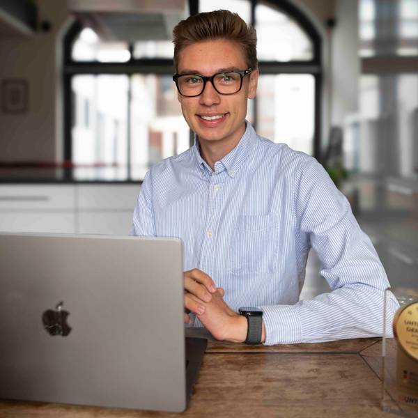 Das Bild zeigt David Schumacher am Küchentisch. Vor ihm steht ein Laptop und der gewonnene Preis.