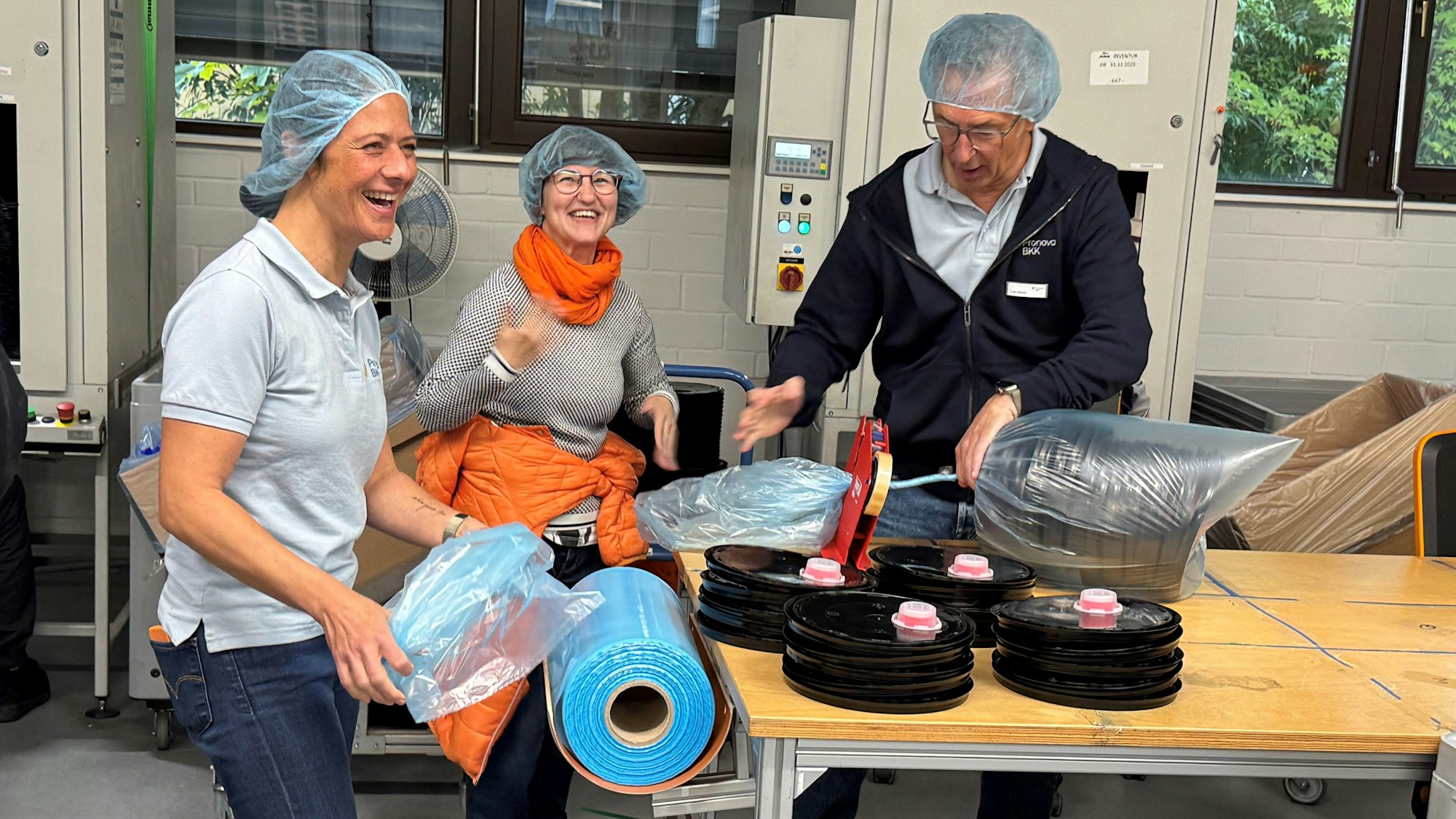 Drei Menschen arbeiten zusammen und lachen dabei.