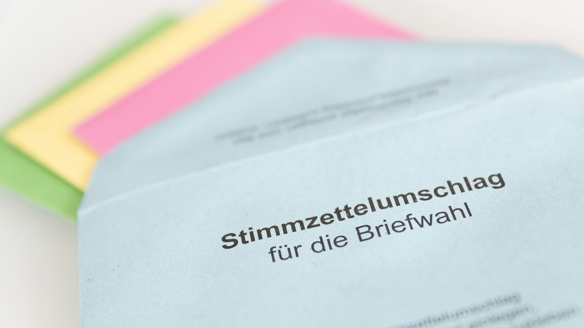 Verschiedene Stimmzettel stecken in einem Stimmzettelumschlag für die Briefwahl.