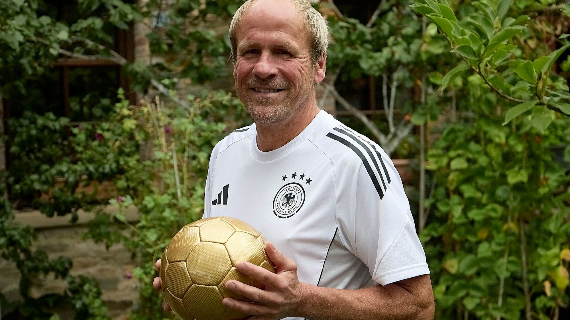 Peter Siebert trägt das Deutschland-Trikot und hält einen goldenen Fußball in den Händen.
