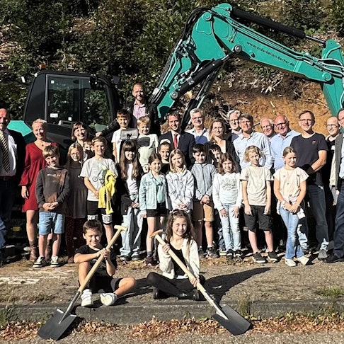 Vor einem Bagger stehen Bürgermeister Christoph Nicodemus sowie Schülerinnen und Schüler der Gemeinschaftsgrundschule Overath.