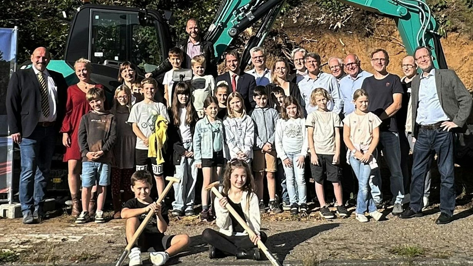 Vor einem Bagger stehen Bürgermeister Christoph Nicodemus sowie Schülerinnen und Schüler der Gemeinschaftsgrundschule Overath.