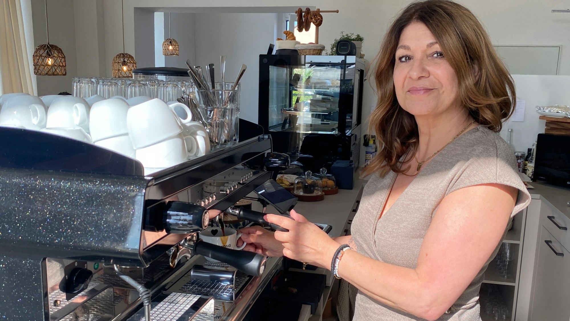 Marisa Flommersfeld-Arévalo steht in ihrem Café in Weilerswist an einer Kaffeemschine.