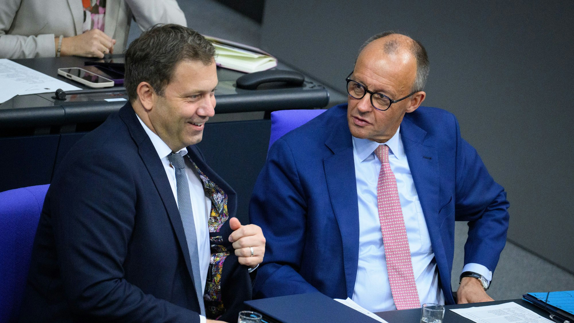 Lars Klingbeil (links, SPD), Bundesminister der Finanzen, und Bundeskanzler Friedrich Merz (CDU) sitzen im Bundestag nebeneinander.