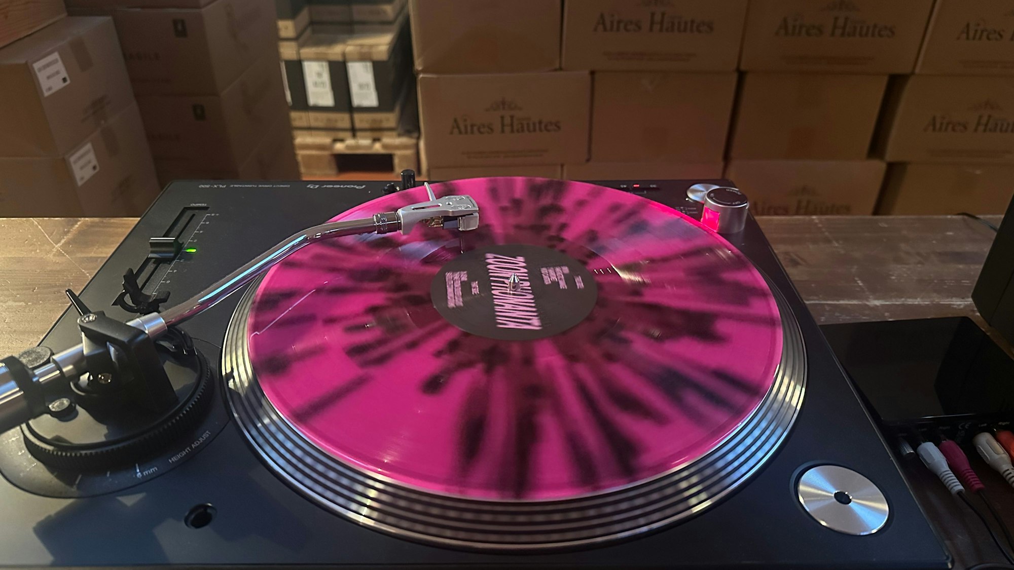 Das Bild zeigt einen Plattenspieler und Weinkartons.