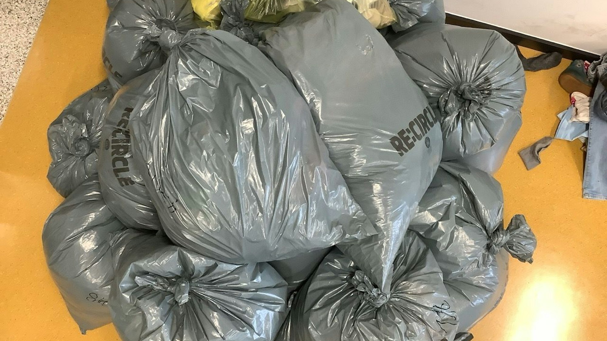 Jugendliche sitzen vor Kleiderstapeln