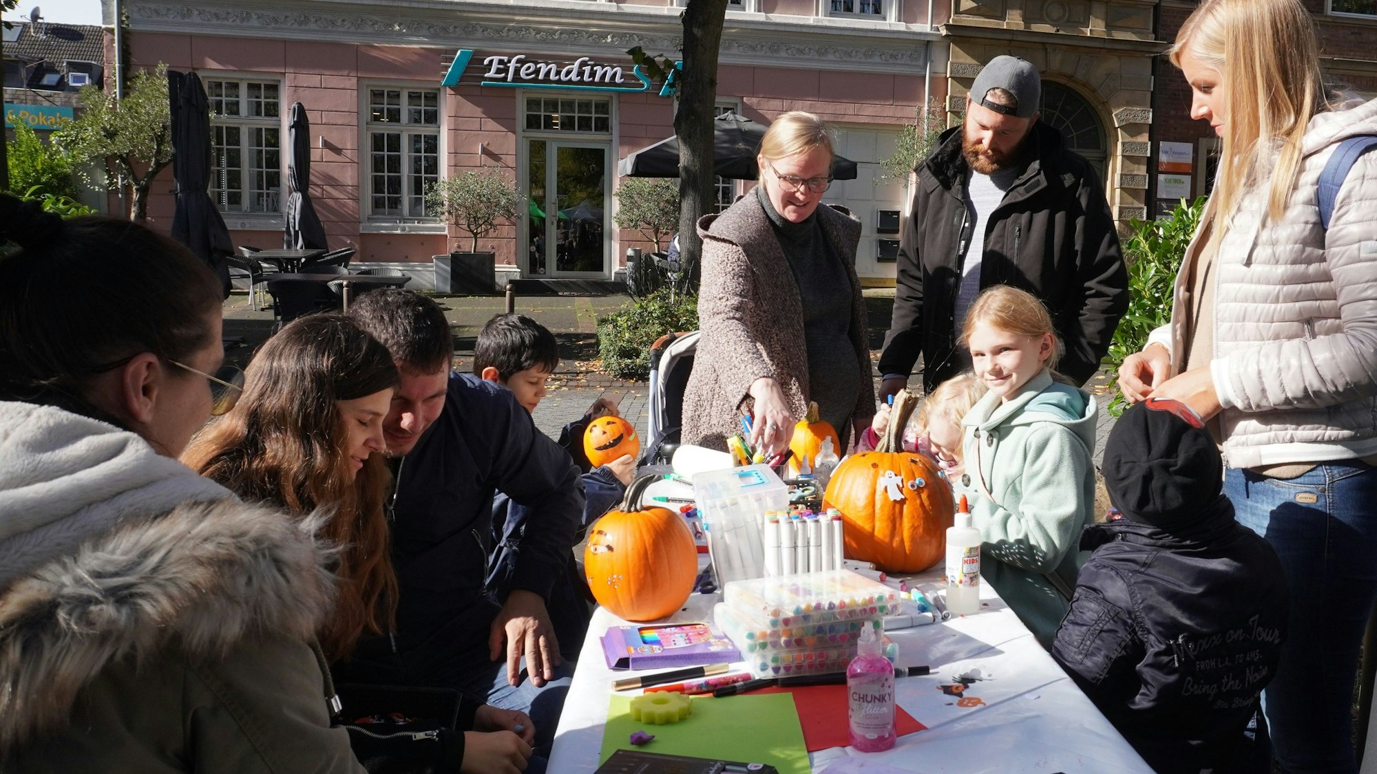 Das Foto zeigt Besucher des Bauernmarkts in Kerpen beim Verzieren von Kürbissen.