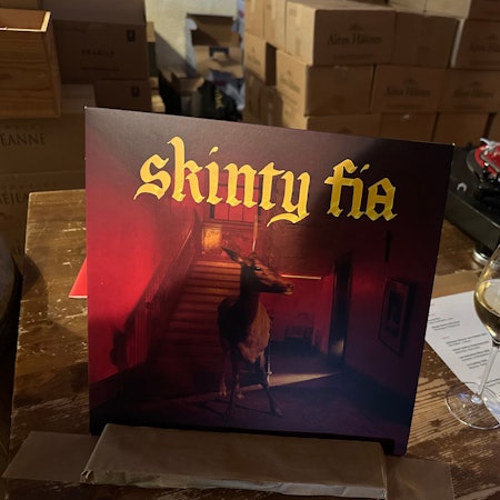 Das Bild zeigt einen Plattenspieler, eine Vinyl und ein Weinglas in der Lagerhalle.