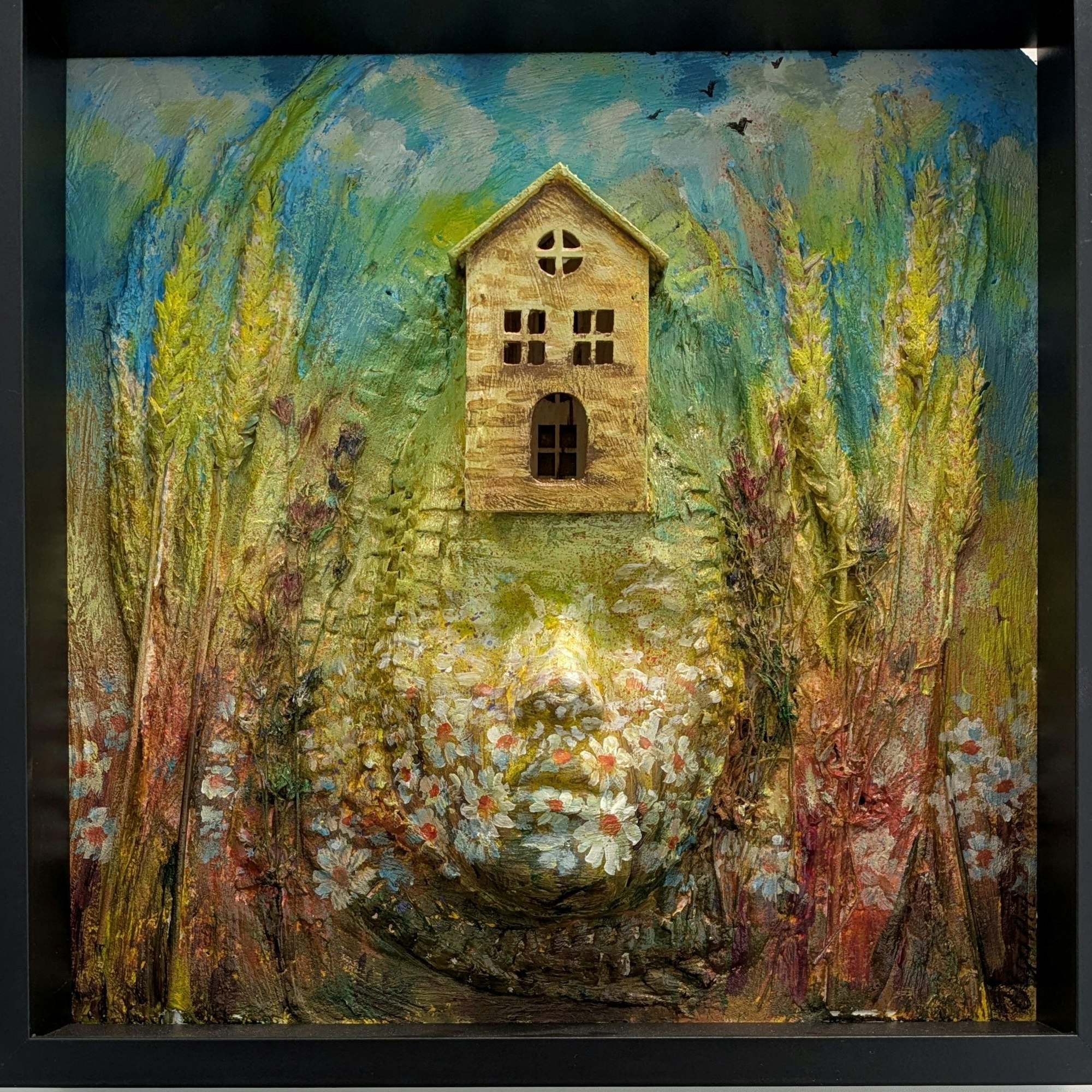 Auf diesem dreidimensionalen Bild ist ein menschliches Antlitz zu sehen, auf dessen Kopf ein kleines, gemütlich wirkendes Häuschen thront. Eingerahmt wird das Ensemble von Getreideähren und Blumen auf einem Feld.