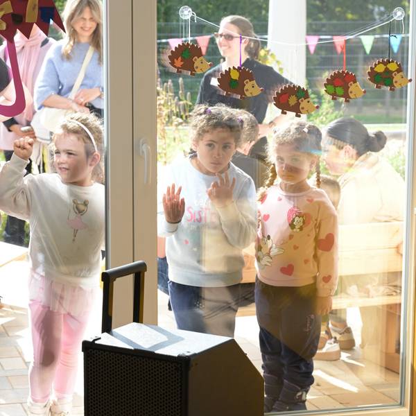 Vier Kinder blicken durch die Fensterscheibe.