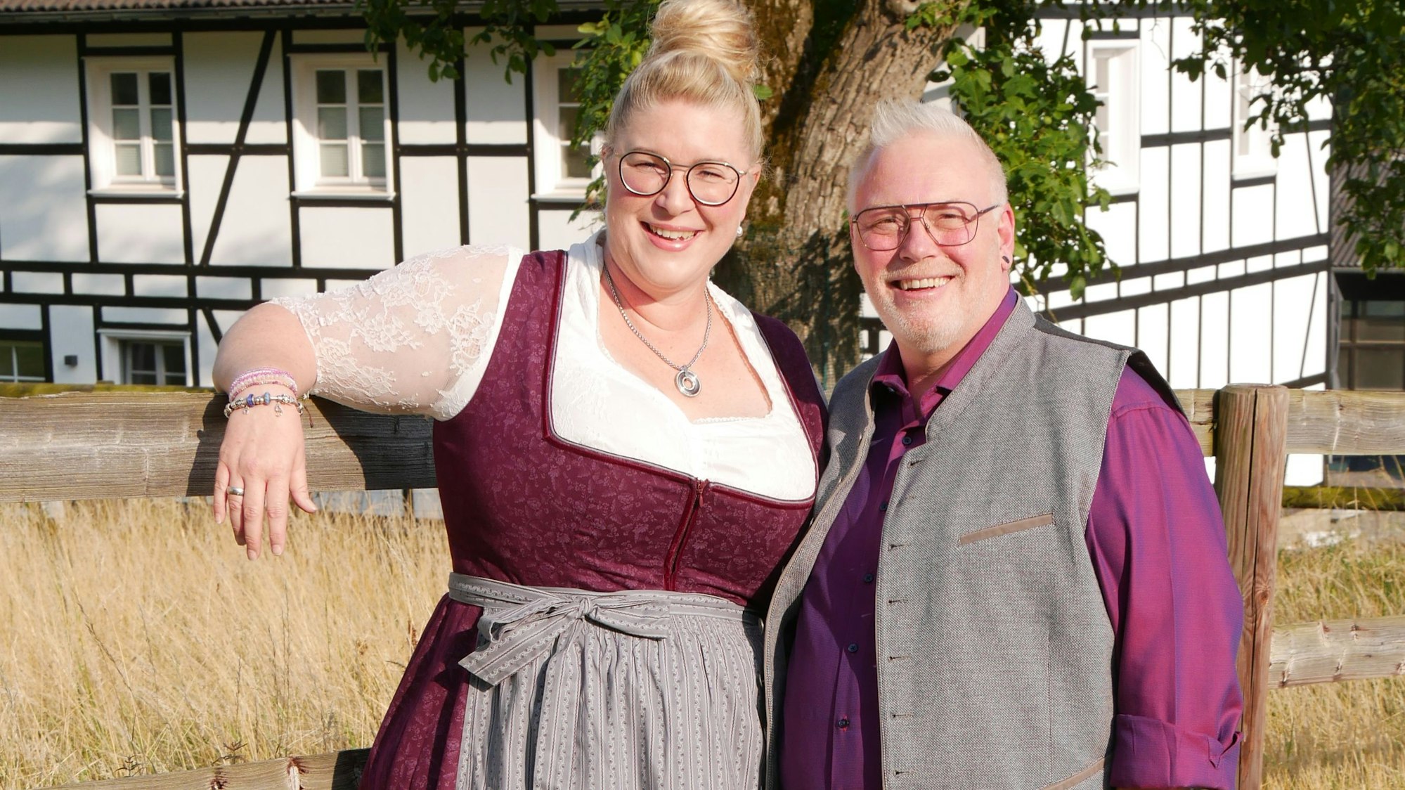 Das Vilkerather Erntepaar 2025 steht an einem Zaun vor einem Fachwerkhaus.