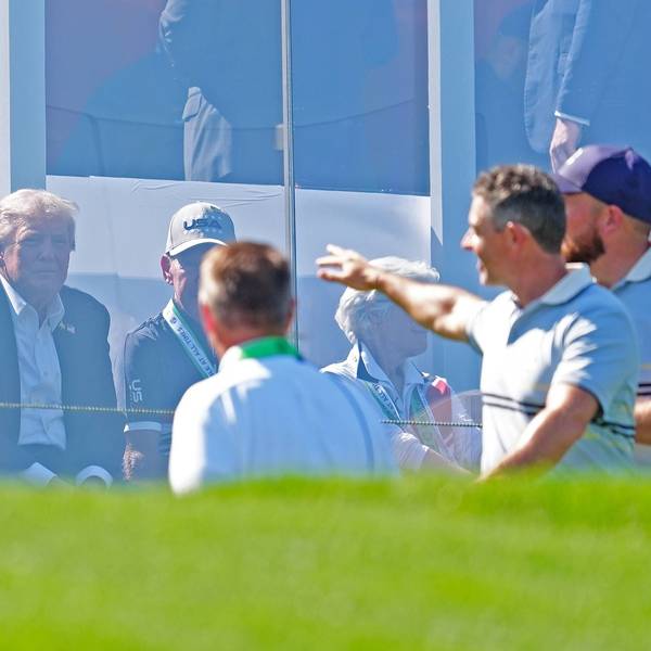Donald Trump sitzt hinter Plexiglas, während Rory McIlroy ins Publikum grüßt.