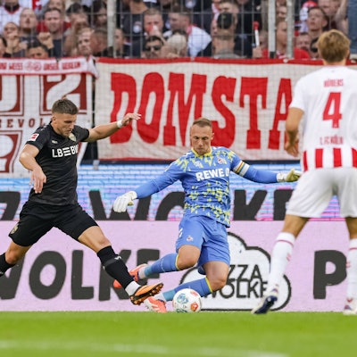 Ermedin Demirovic ist vor Marvin Schwäbe am Ball, der Kölner Torwart klärt auf Kosten eines Elfmeters.