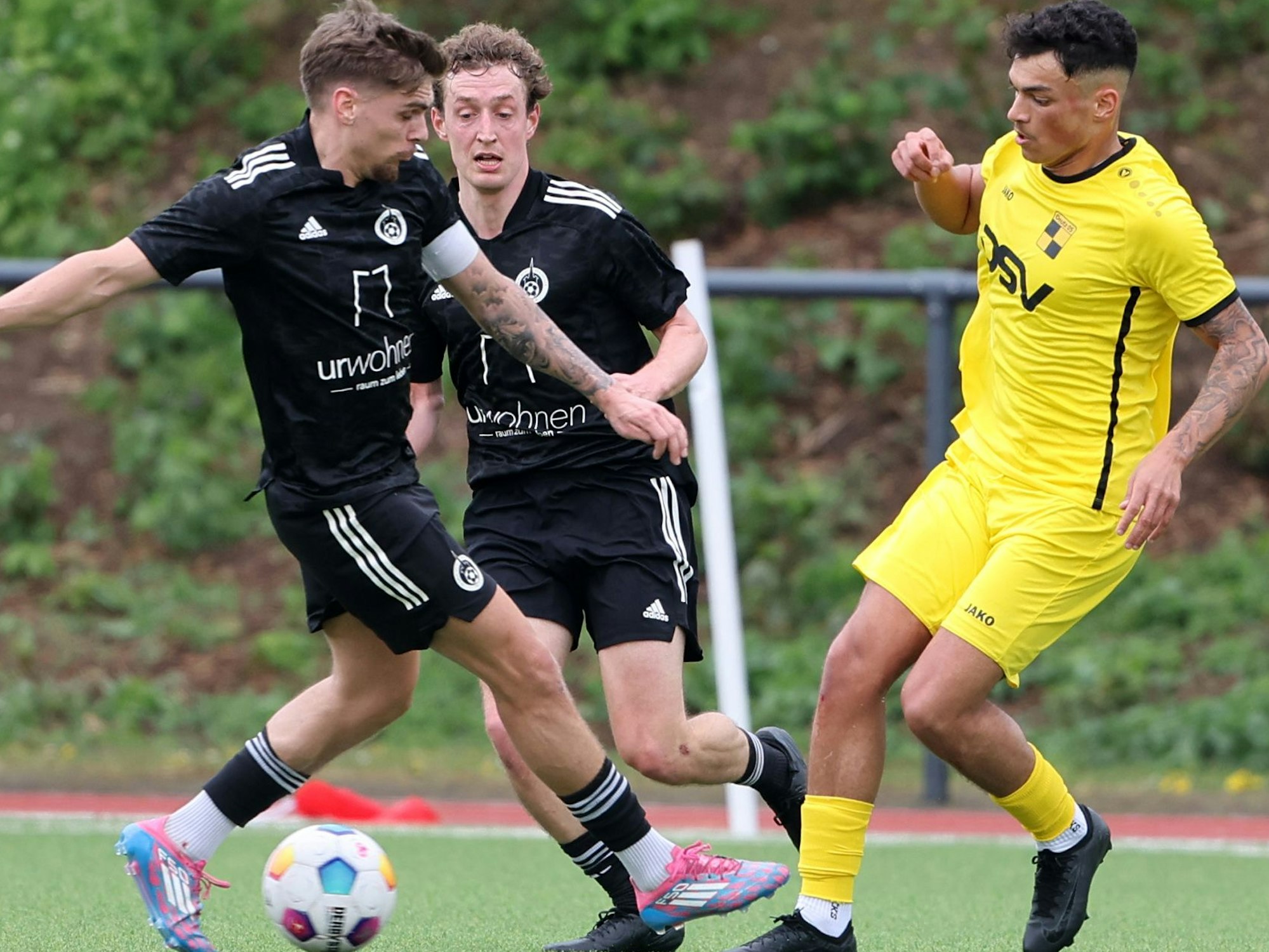 Das Bild zeigt einen Fußballer im dunklen Trikot aus Brauweiler im Zweikampf mit dem Ball zwischen seinen Füßen.