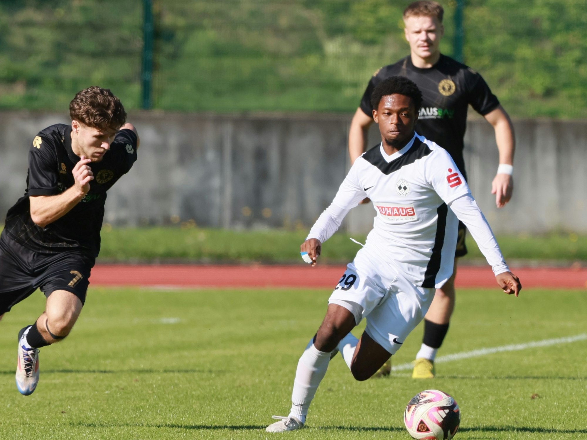 Das Bild zeigt einen Fußballer im hellen Trikot, der seinem dunkel gekleideten Kölner Gegenspieler enteilt.
