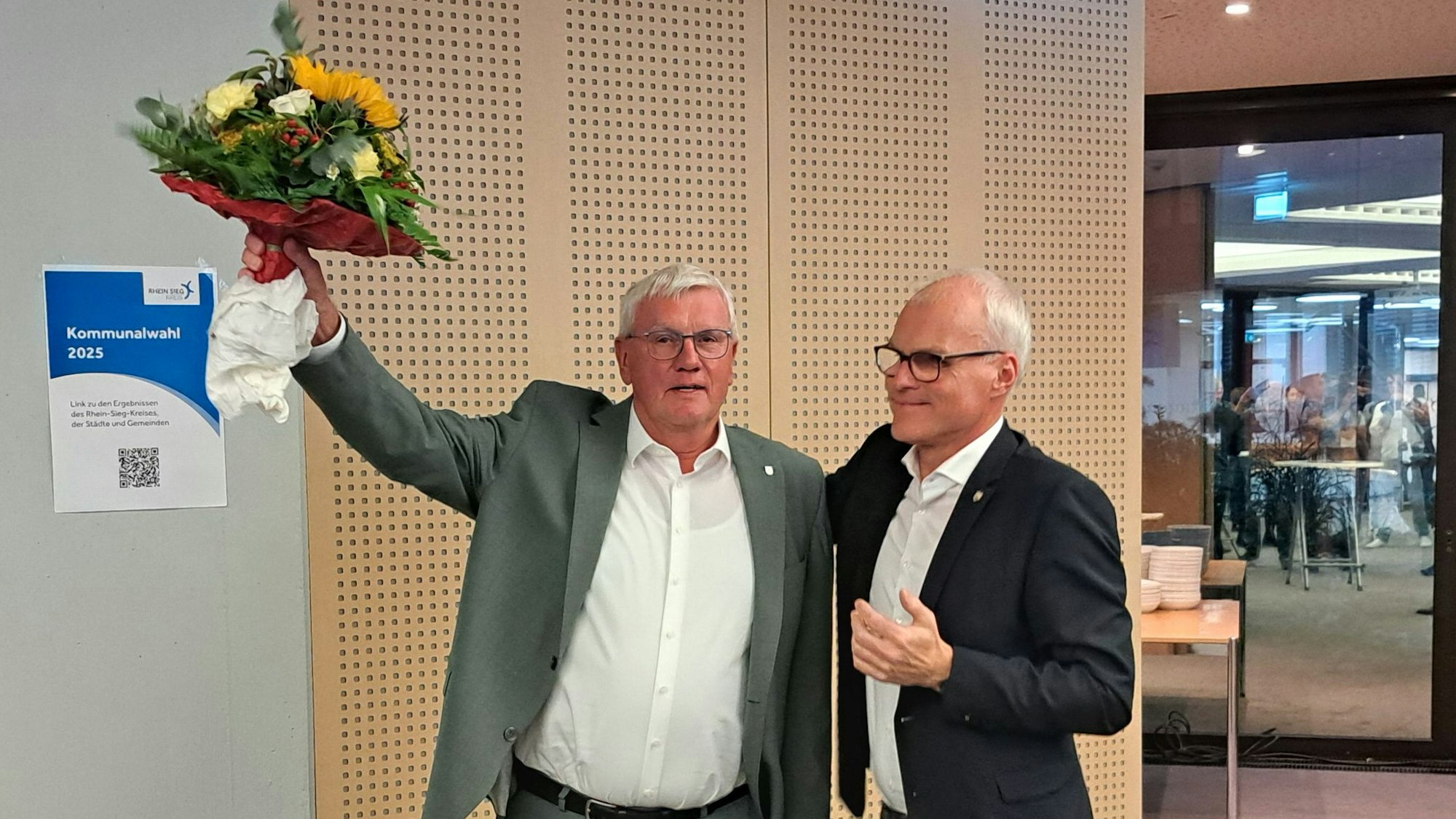 Der im Amt bestätigte Landrat Sebastian Schuster (CDU) hält den Blumenstrauß in die Höhe, den er von dem neben ihn stehenden CDU-Kreisvorsitzenden Oliver Krauß bekommen hat.