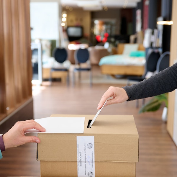 Ein Wahlumschlag wird in die einem Wahlraum in einem Bettengeschäft in die Urne gesteckt. (Symbolbild)