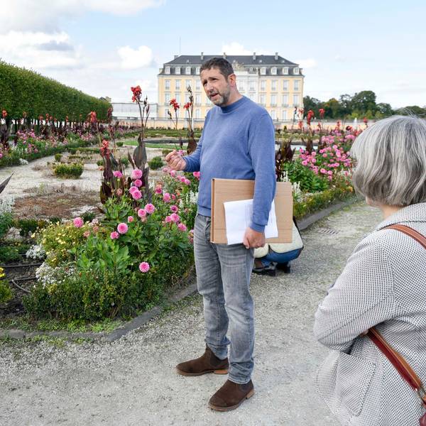 Zu sehen ist Ufuk May, der mit Besuchern des Schlossparks spricht.