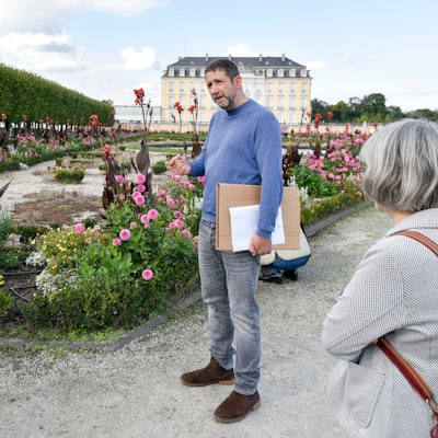 Zu sehen ist Ufuk May, der mit Besuchern des Schlossparks spricht.