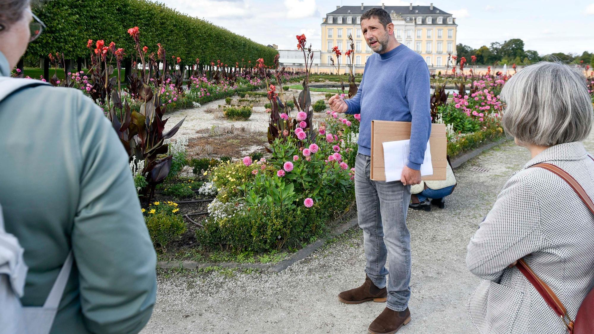 Zu sehen ist Ufuk May, der mit Besuchern des Schlossparks spricht.