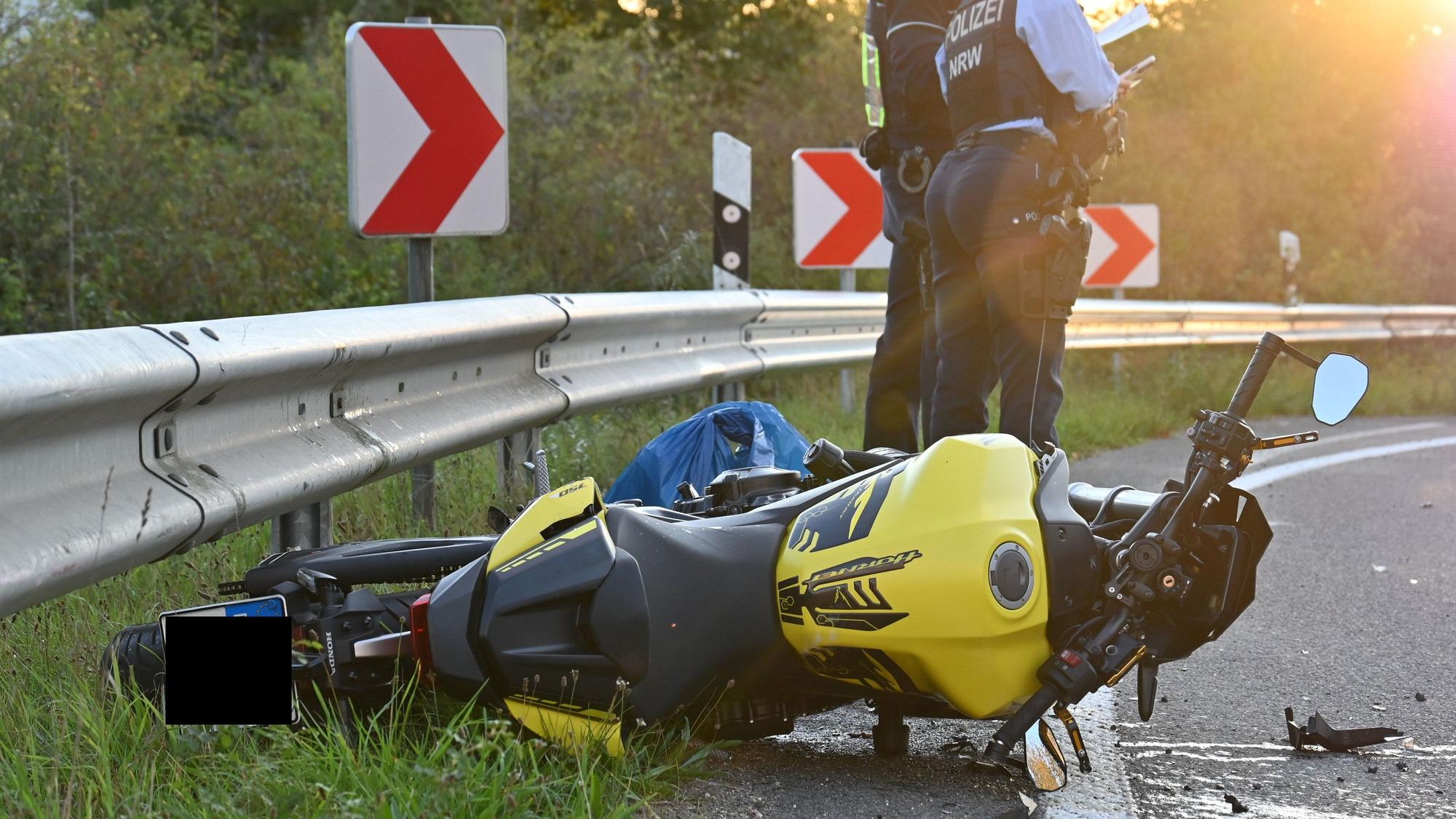 Das Bild zeigt ein Motorrad an einer Leitplanke und zwei Polizeibeamte.